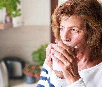 senior woman sipping a cup of tea in kitchen