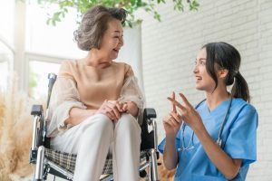 young caregiver helping senior woman in LTC