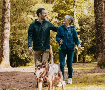 man and senior woman walking dog outdoors