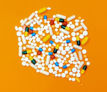 white and colored prescription pills on orange background