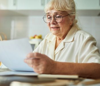 senior woman in glasses looking at life insurance document