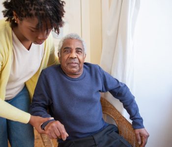 woman helping senior man in chair